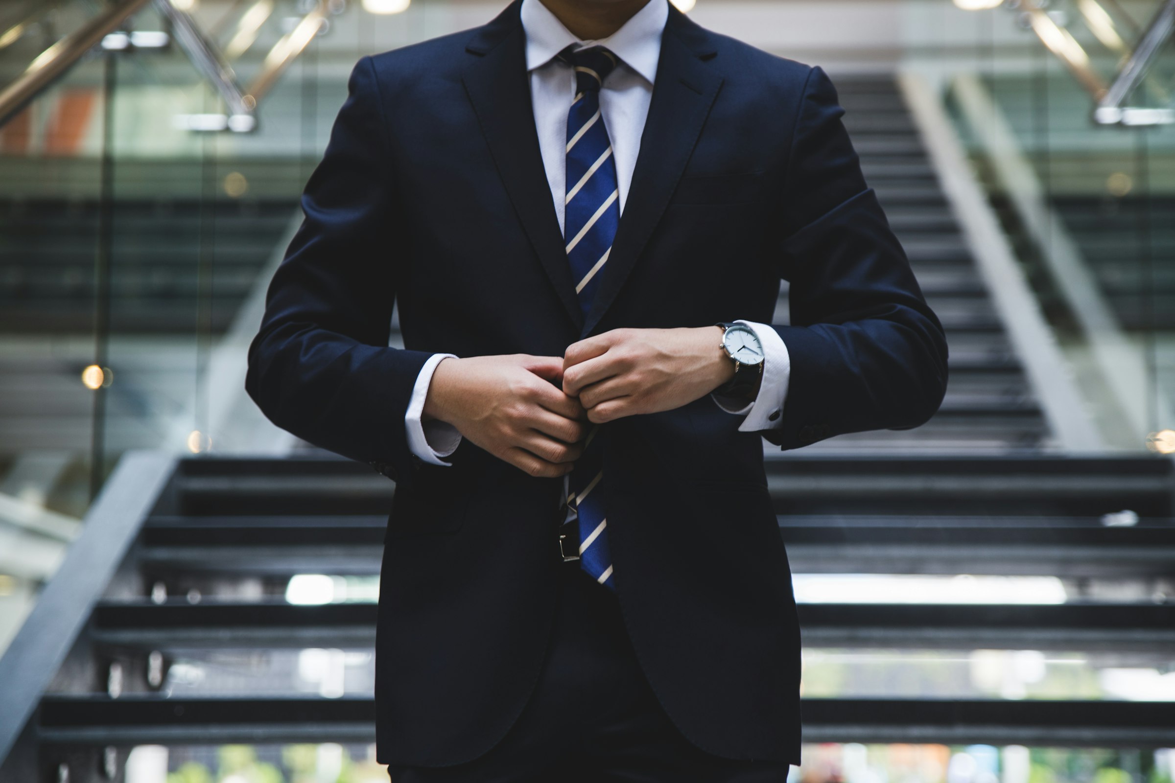 A gentleman fastening the cuff of a tailored suit jacket